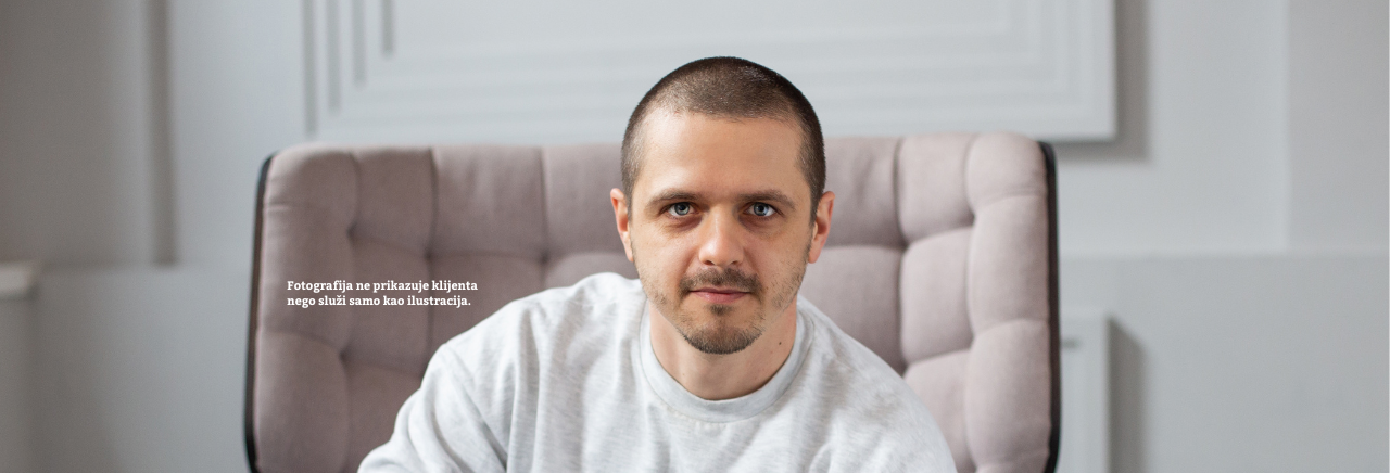 Muškarac kratke kose sjedi u udobnoj, tapeciranoj fotelji u svijetloj prostoriji i gleda prema kameri. Fotografija služi kao ilustracija.